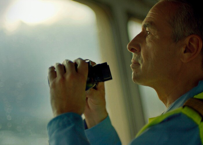 Oficial mirando hacia el puerto con binoculares