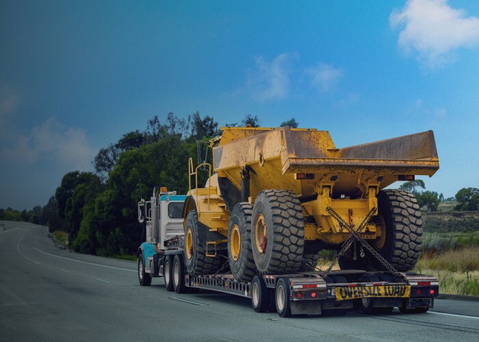Mining Logistics services – An open flatbed truck of Maersk carrying the mining machinery in Africa.