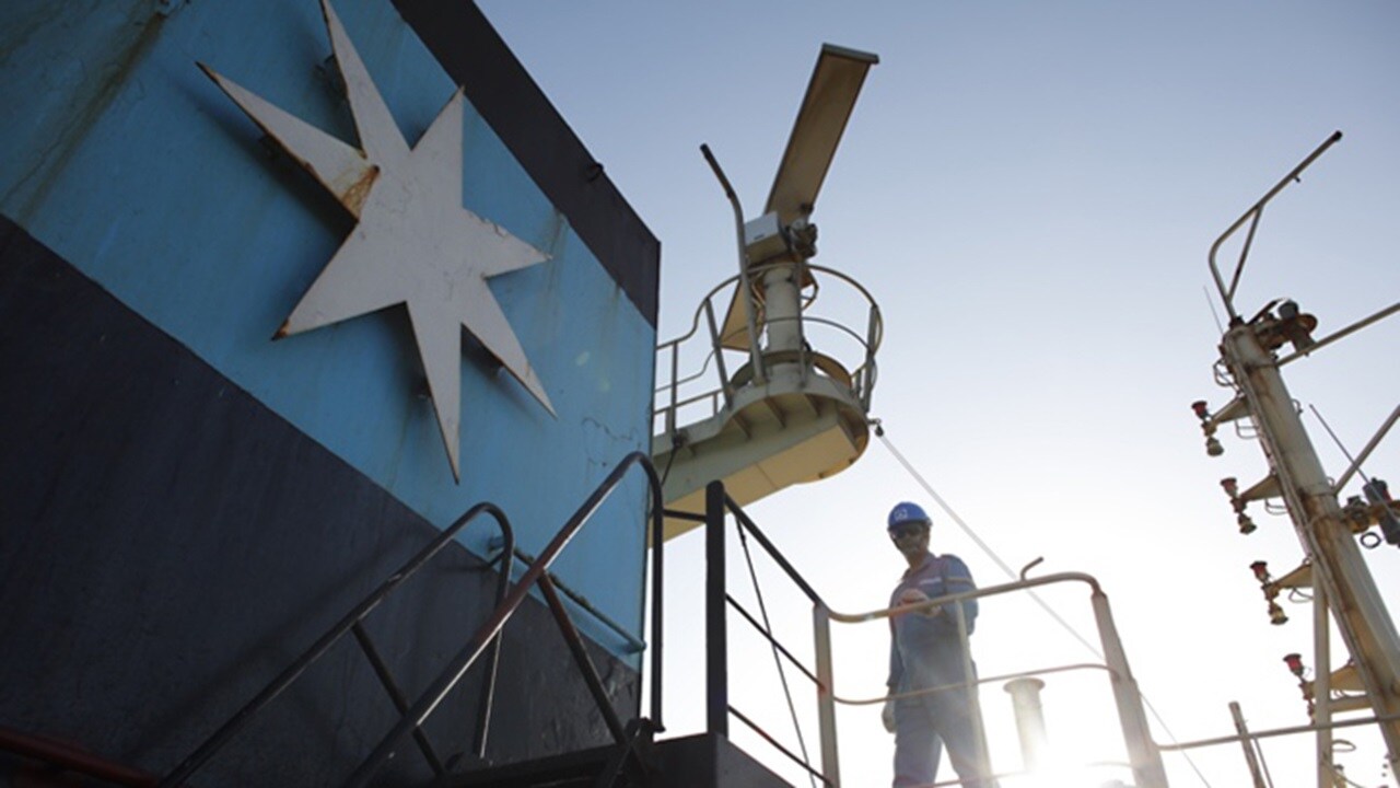 Man in uniform and hard hat standing on exterior bridge