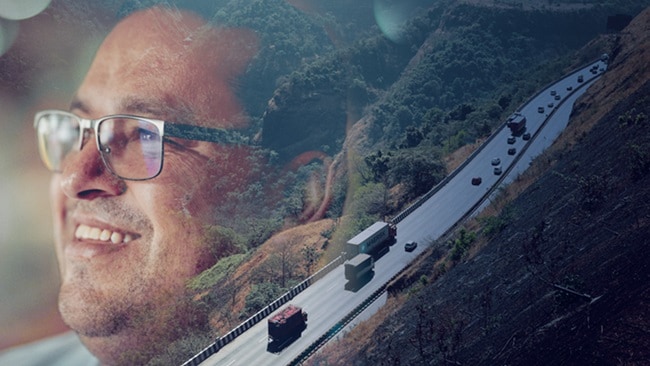 A smiling man wearing glasses looks into the distance. His face is overlaid with the image of a road where several trucks and cars are seen from above.