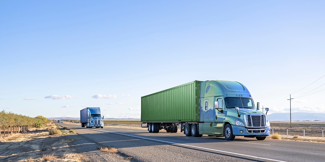 Two large trucks traveling down a highway.