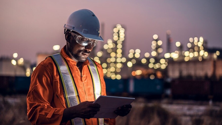 Man with safety helmet and reflective vest looking at a tablet computer  