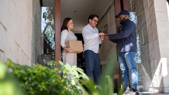 Young couple receiving a package from the delivery person at their front door