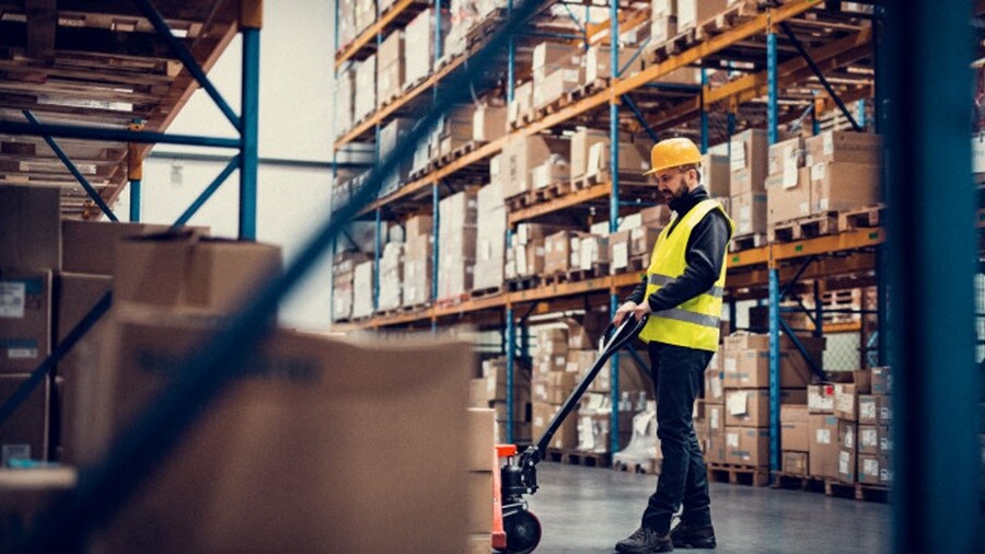 Man with yellow helmet standing inside a warehouse