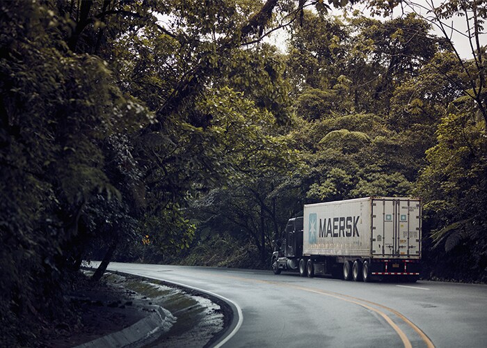 Maersk truck driving along a curved road with trees on both the ends