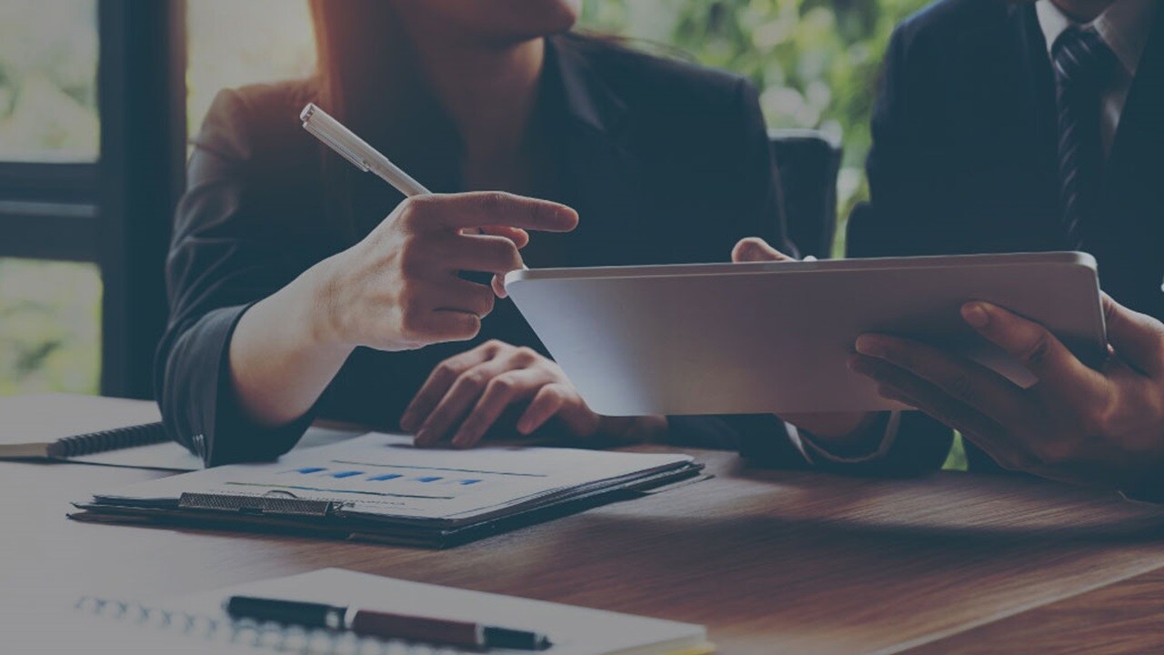 Two sets of hands working on a tablet