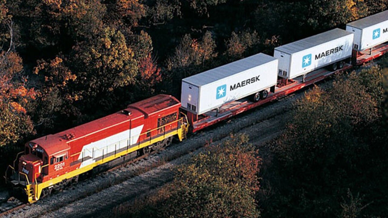 Vista aérea de un tren que transporta contenedores de Maersk con carga refrigerada.
