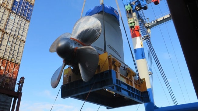 A large ship’s propeller is being lifted by a crane