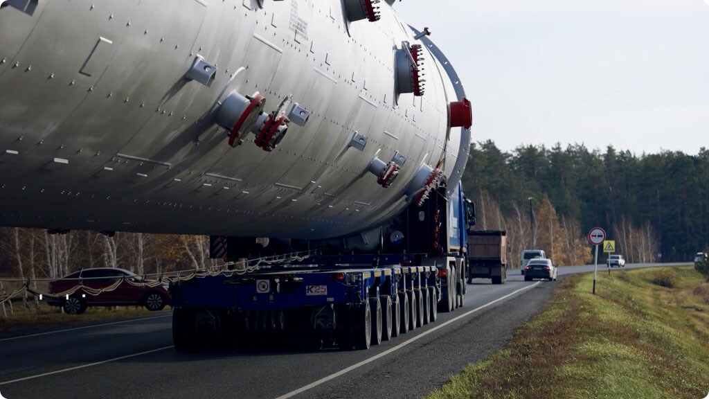 A large truck drives down the road, carrying a sizable object on its flatbed.