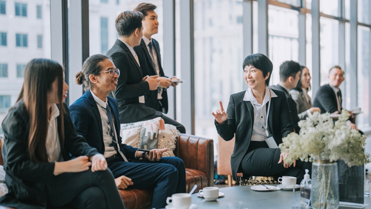  Business professionals engaged in discussion while seated on couches in a modern office setting.