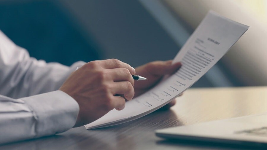 Hands holding a pen and papers