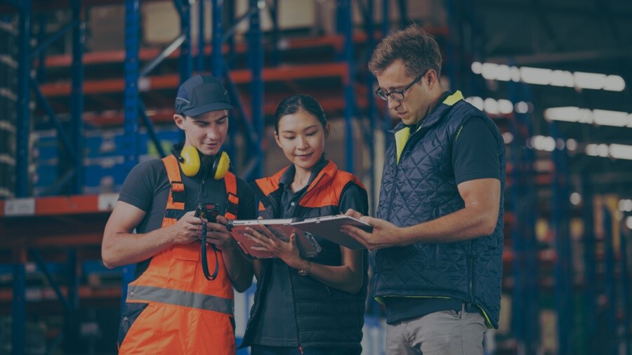 Two male and a female looking at a tablet in the warehouse