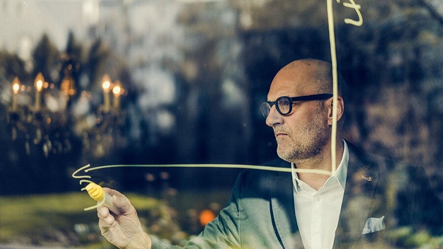 A picture of a man drawing a graph on glass.