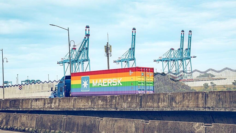 Truck with a Maersk rainbow container leaving a terminal.