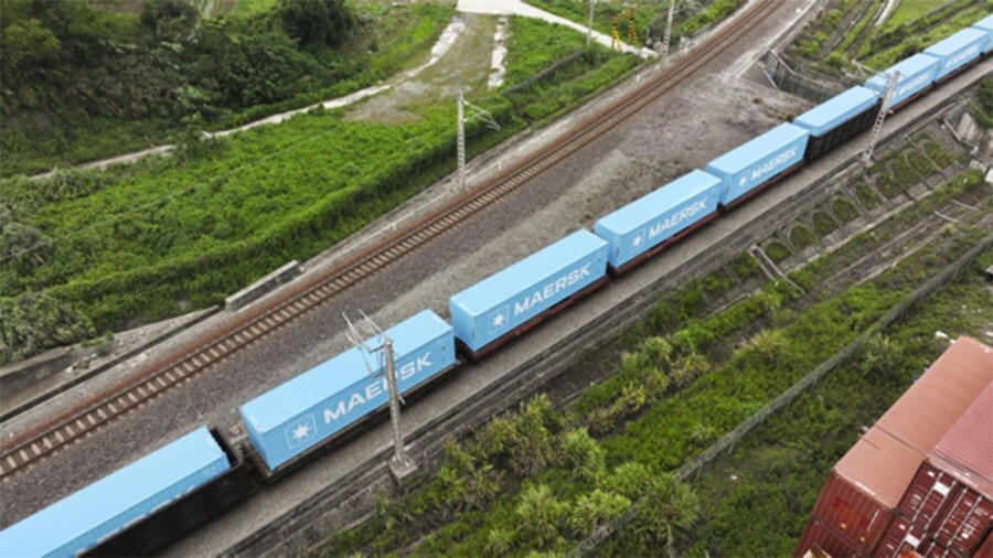A train with blue cars travels along a track, showcasing its movement through a scenic landscape.