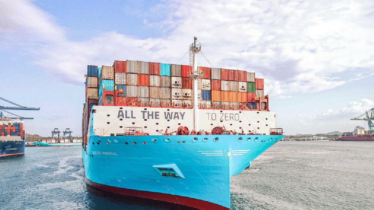 A prominent blue and white ship floating on the water, reflecting its colors in the gentle waves surrounding it.