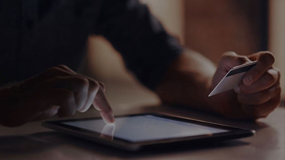 Close-up of a person’s hand making online payment using their credit card on their tablet.