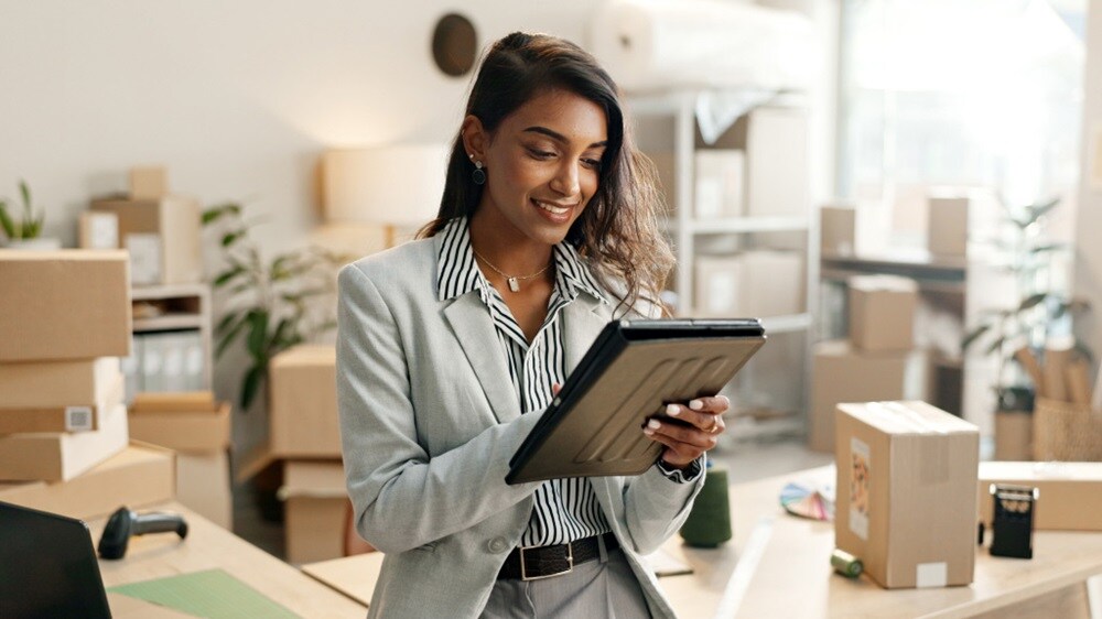 A woman in a business suit holding a tablet, appearing focused and engaged in her work.