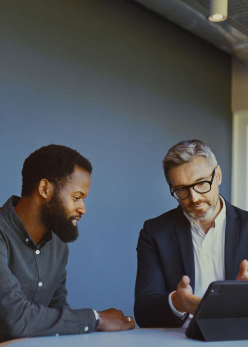 Two businessmen are discussing the ECTN essentials using a digital tablet.