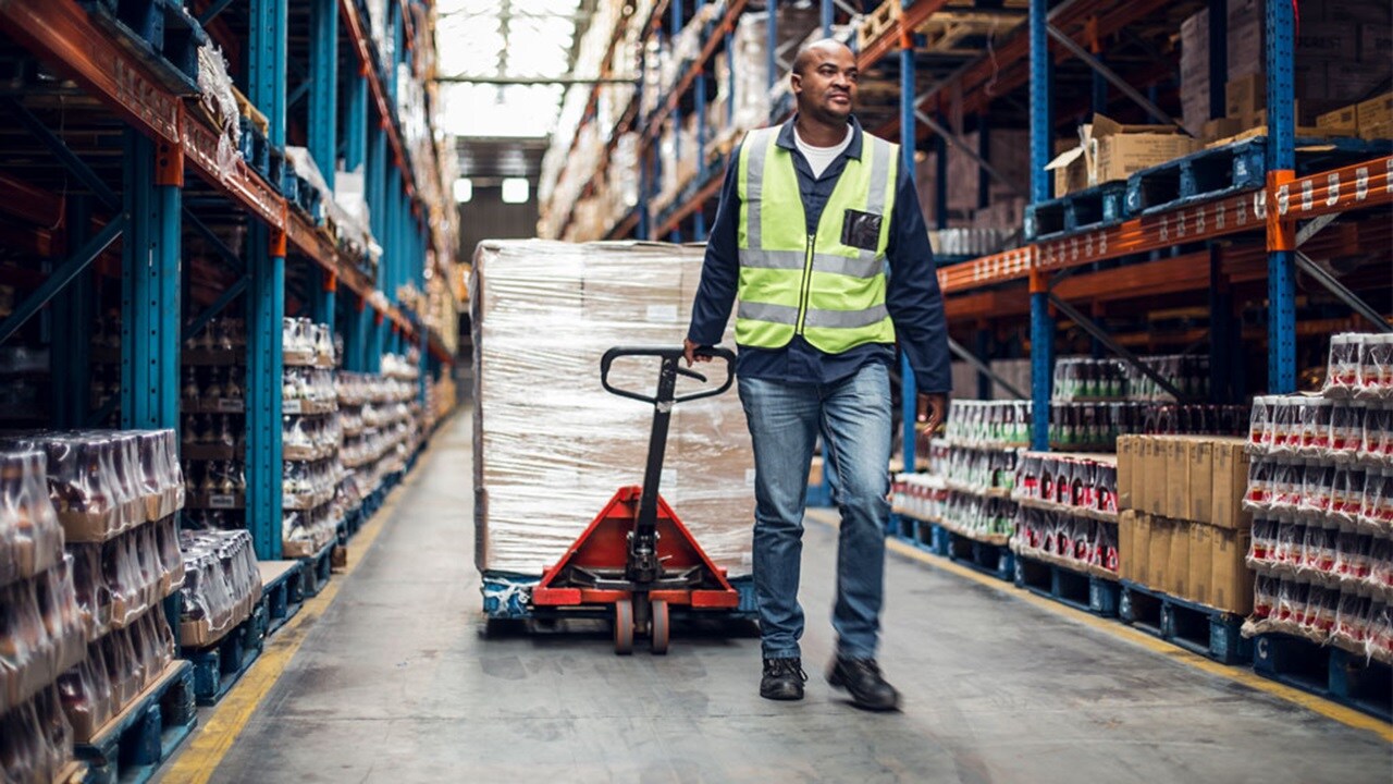 A worker wheeling small shipments in a cargo warehouse.