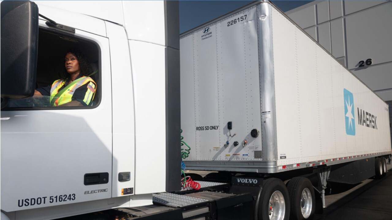 A female truck driver checking the rear-view mirror before starting a road trip