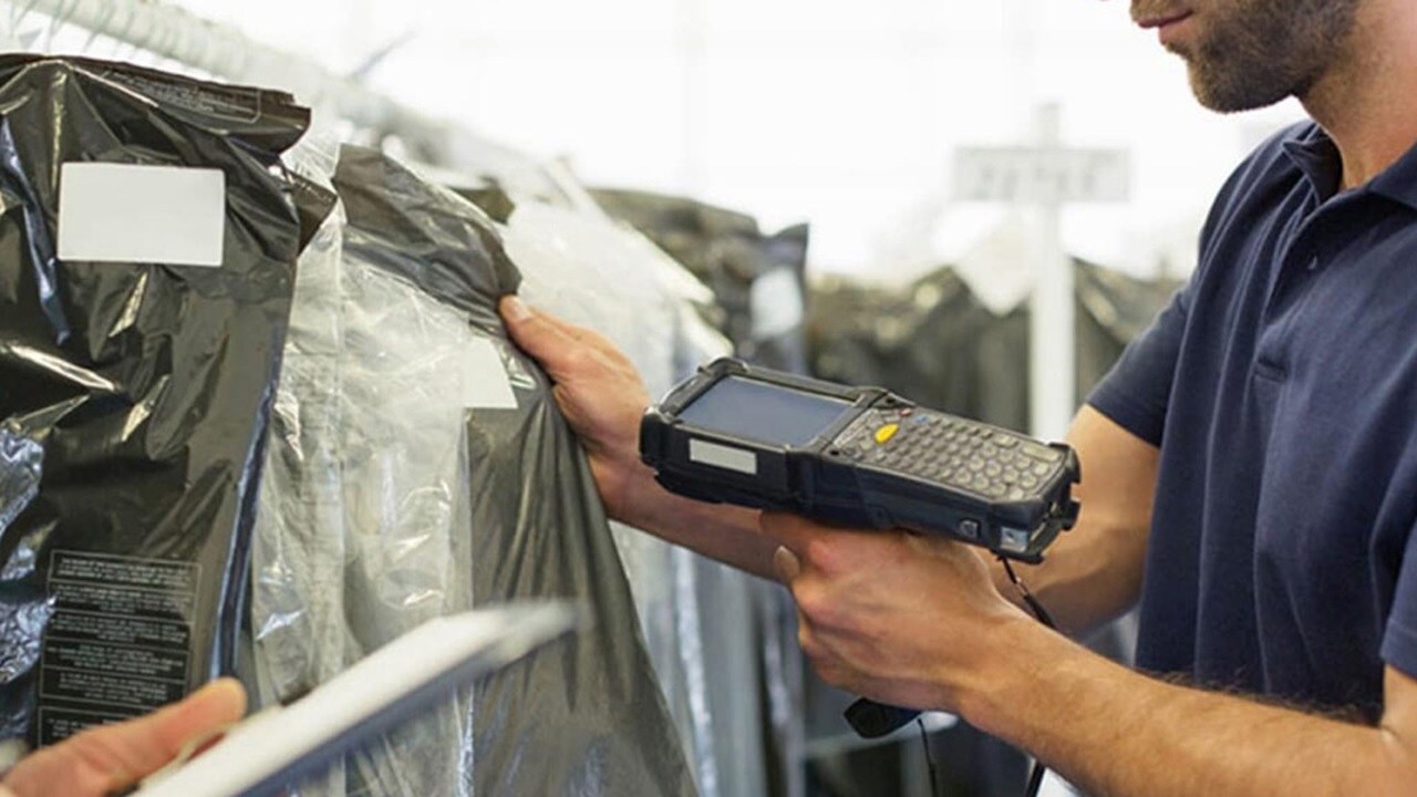 A worker uses a handheld scanner to scan the barcode on each garment to ship.